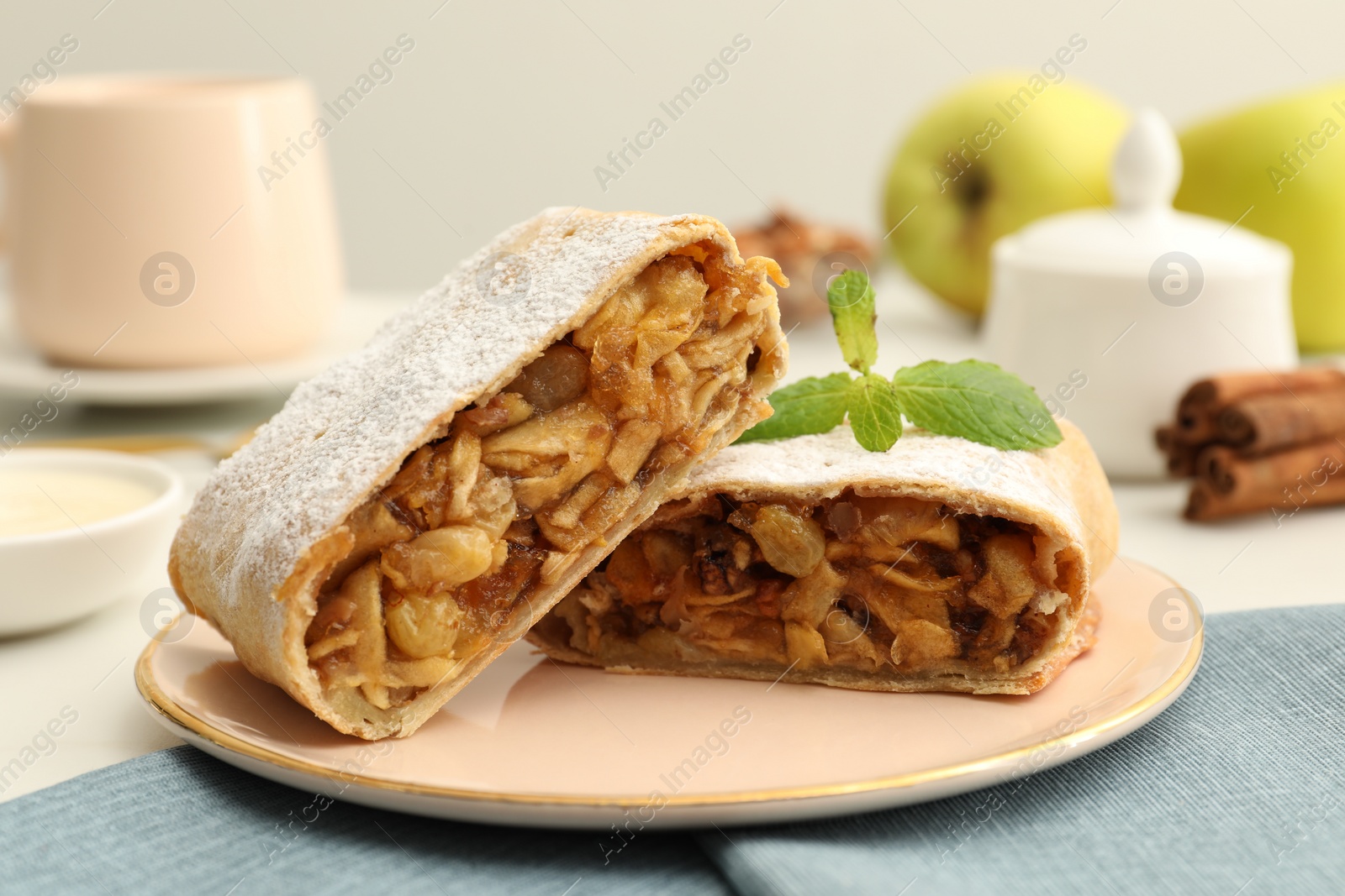 Photo of Delicious strudel with apples, nuts and raisins on table, closeup