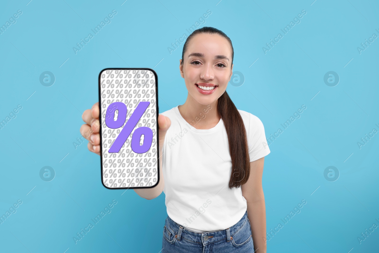 Image of Discount, offer, sale. Woman showing mobile phone with percent signs on screen, light blue background