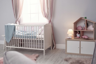 Baby room interior with comfortable crib and dollhouse