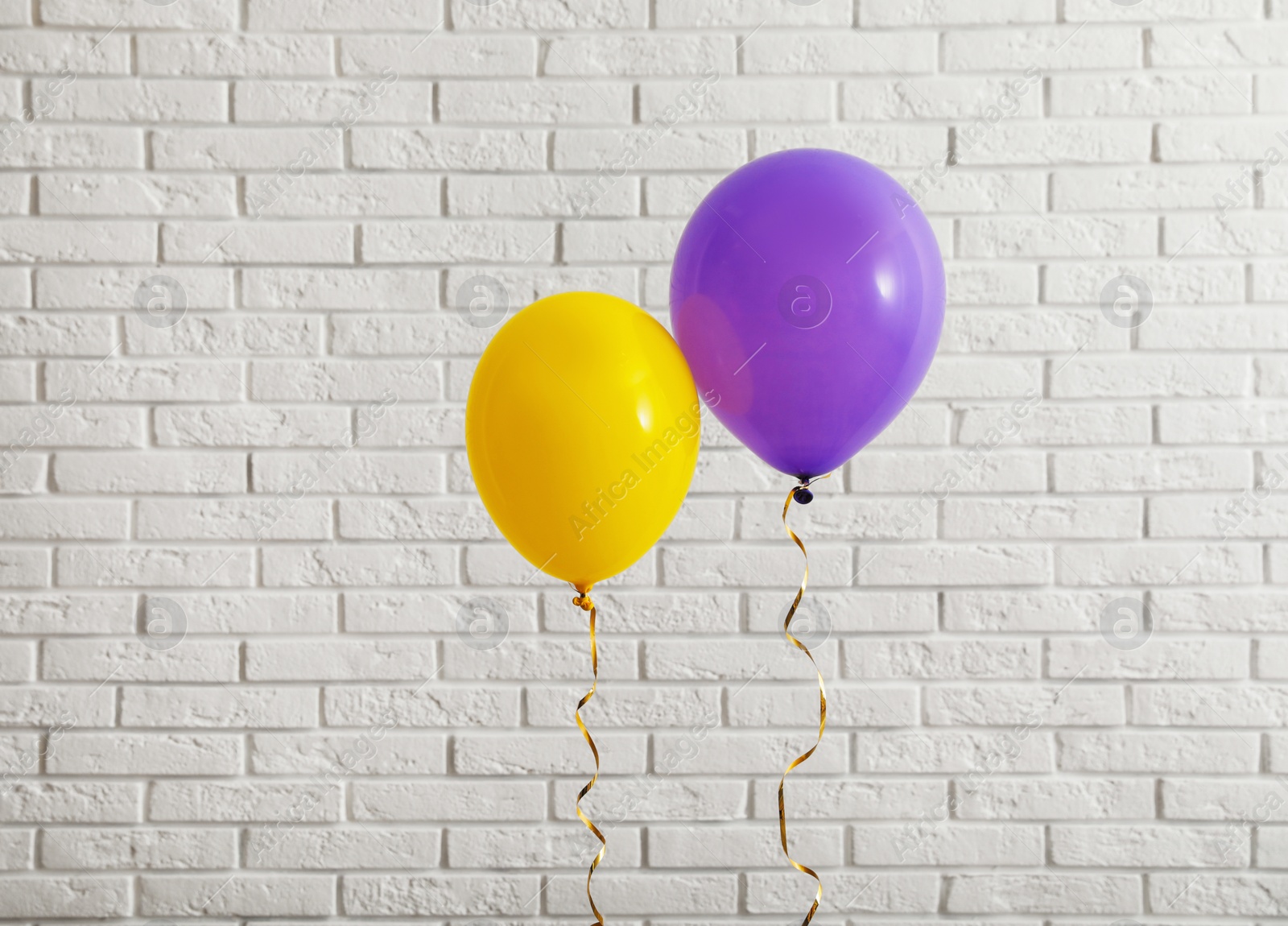 Photo of Bright balloons near brick wall, space for text. Celebration time