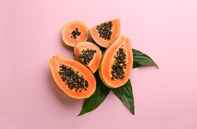 Photo of Fresh ripe papaya fruits with green leaves on pink background, flat lay