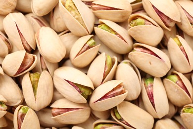 Tasty unpeeled pistachios as background, top view