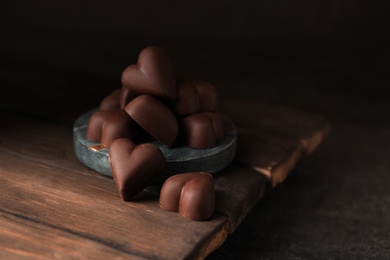 Delicious heart shaped chocolate candies on wooden board
