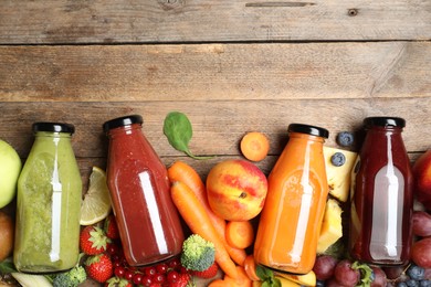 Photo of Bottles of delicious juices and fresh fruits on wooden table, flat lay. Space for text