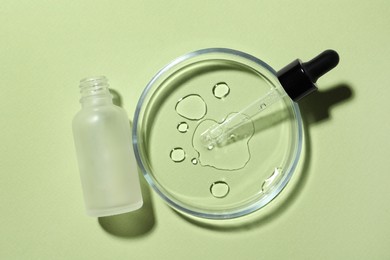 Photo of Petri dish with pipette and bottle on light green background, flat lay