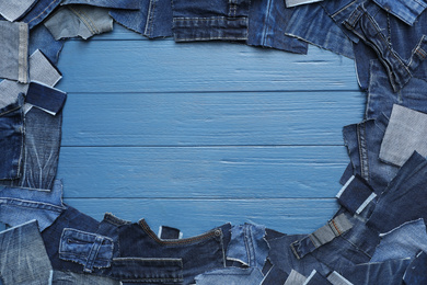 Photo of Frame made of cut jeans on light blue wooden background, flat lay. Space for text