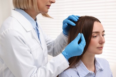Trichologist examining patient`s hair in clinic, closeup