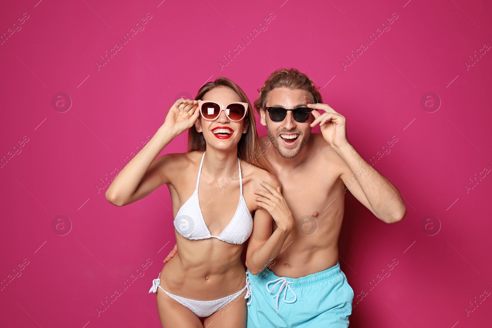 Photo of Happy young couple in beachwear on color background