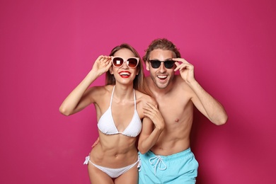 Happy young couple in beachwear on color background