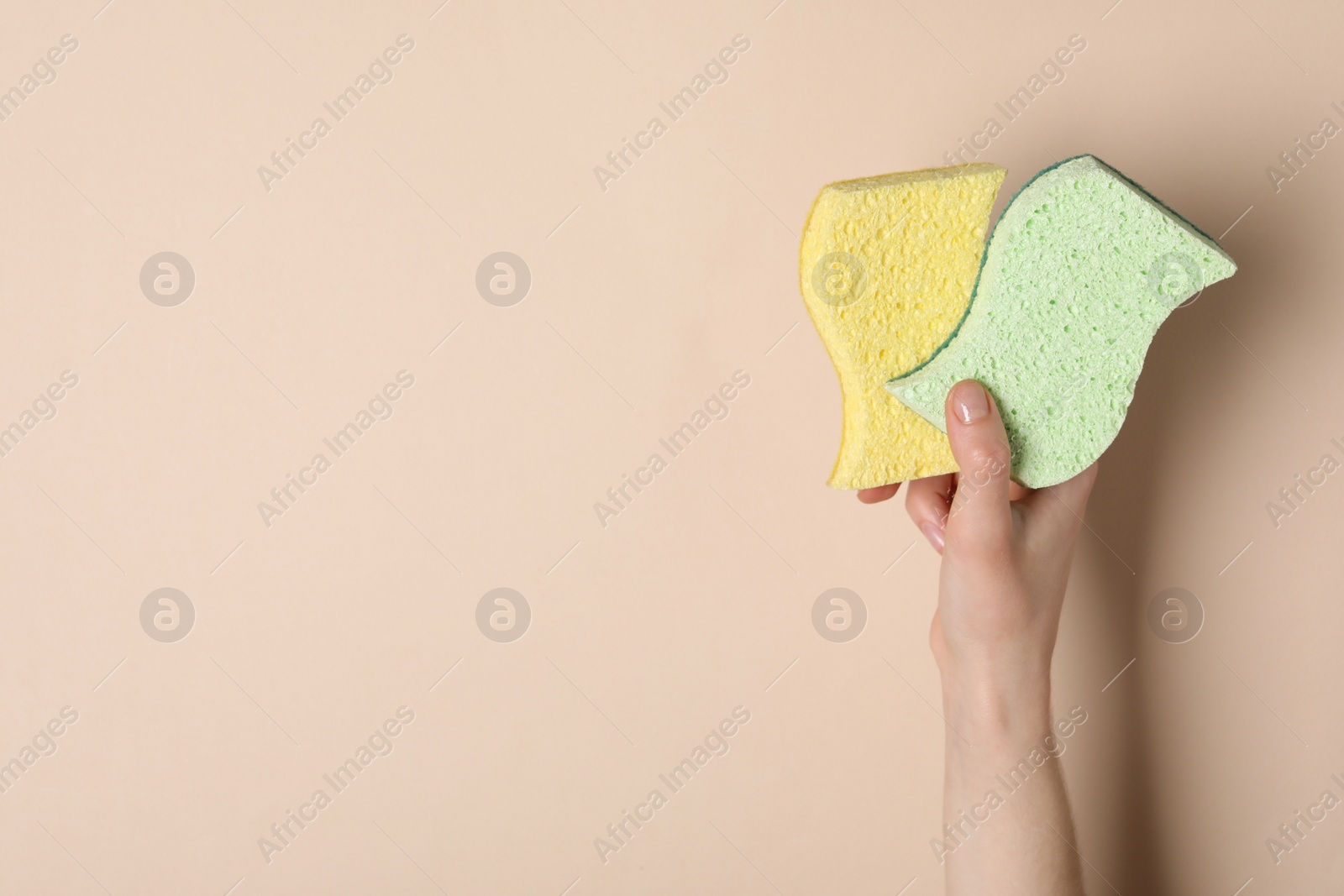 Photo of Woman holding sponges on beige background, top view. Space for text