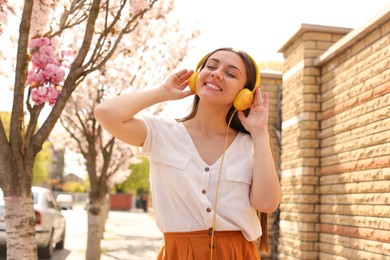 Happy young woman with headphones listening to music on city street