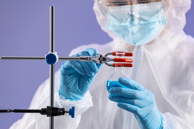 Scientist fixing flask on stand on grey background, closeup