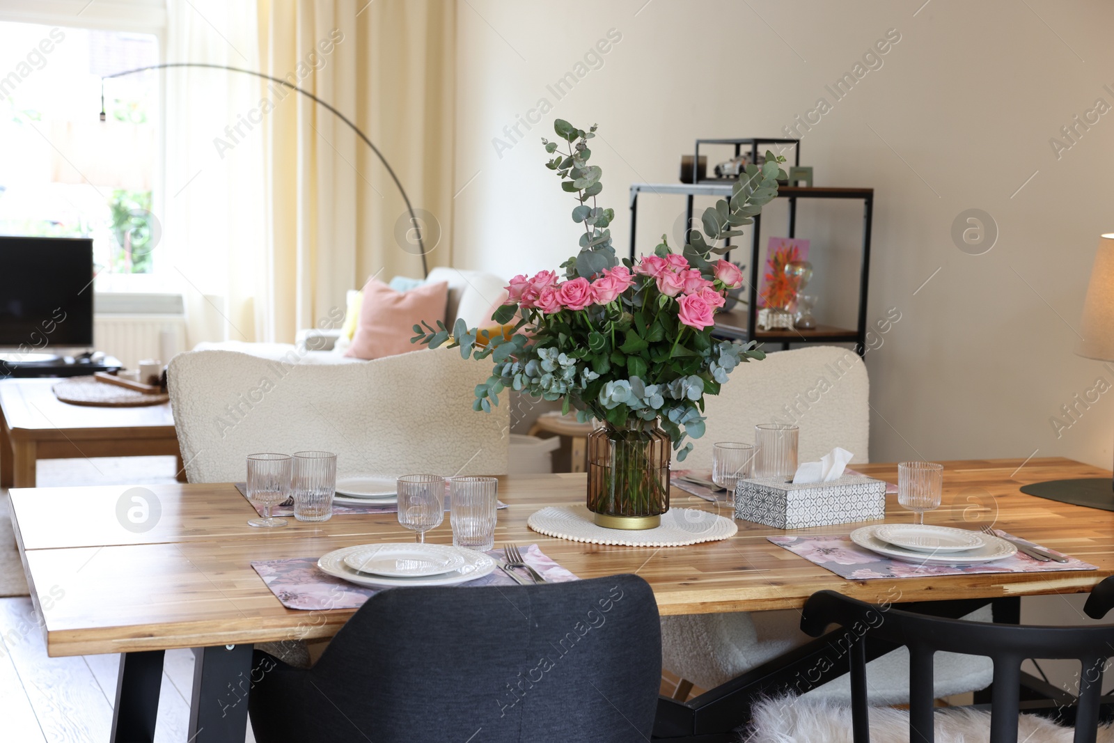 Photo of Beautiful table setting with bouquet in dining room. Roses and eucalyptus branches in vase