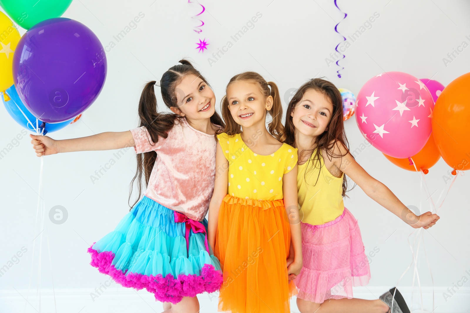 Photo of Adorable little girls and decor for birthday party on light background