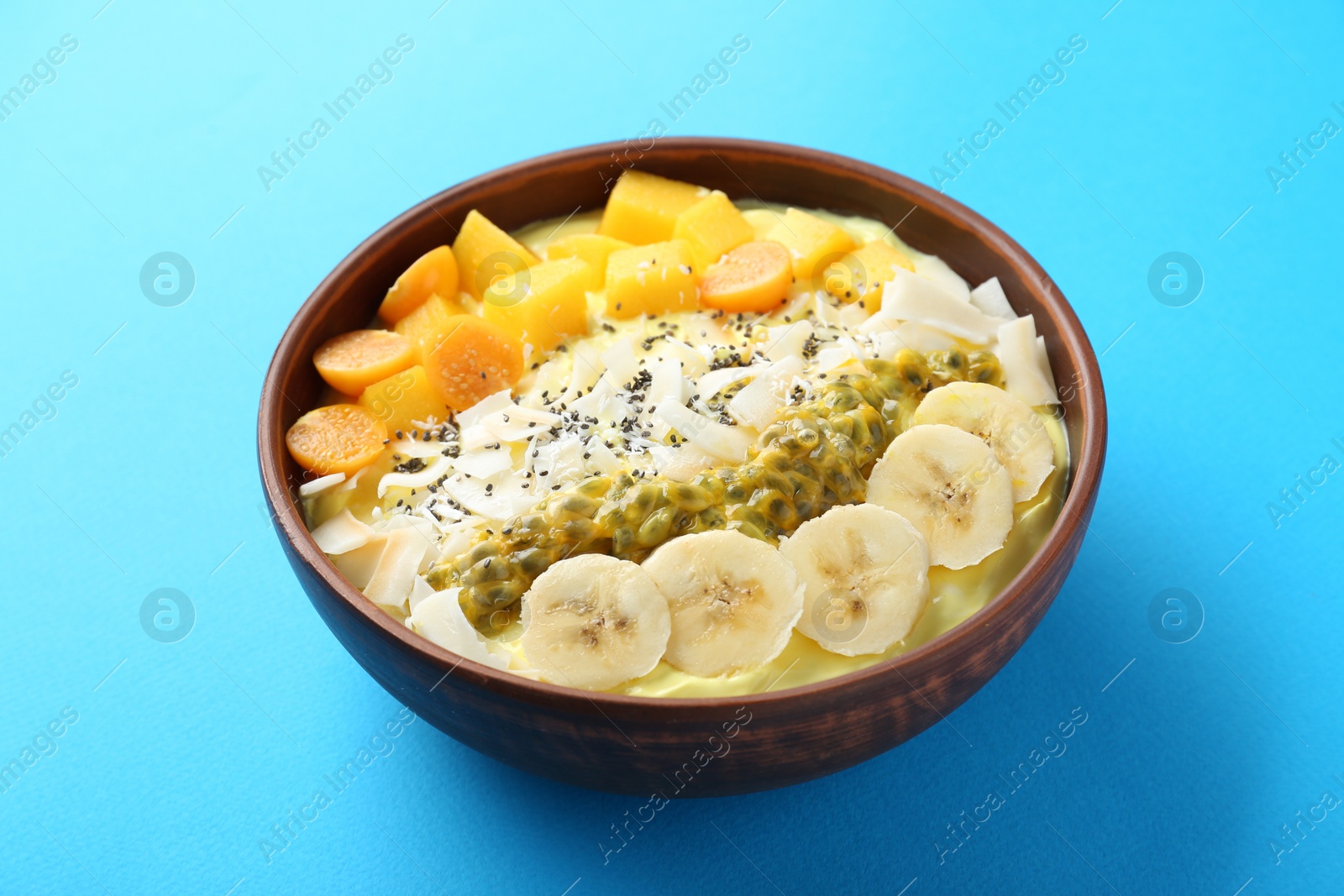 Photo of Tasty smoothie bowl with fresh fruits on light blue table