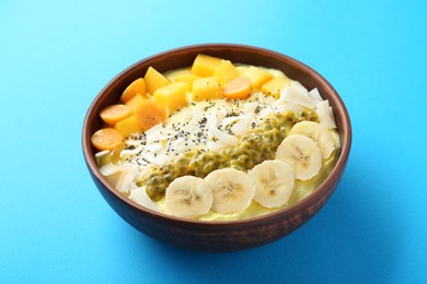 Photo of Tasty smoothie bowl with fresh fruits on light blue table
