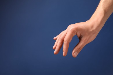 Photo of Man holding something in hand on blue background, closeup. Space for text