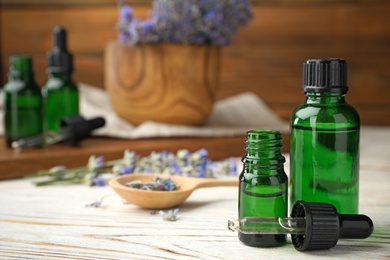 Bottles with natural lavender essential oil on table, space for text