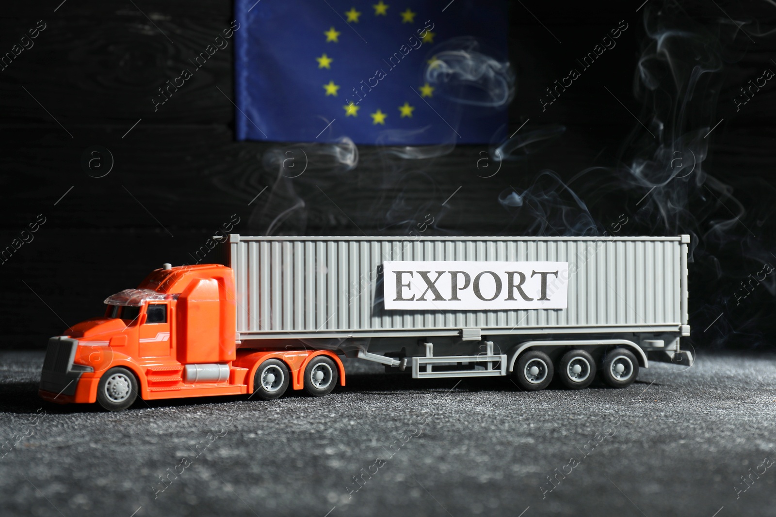 Photo of Toy truck and EU flag on black background. Export concept