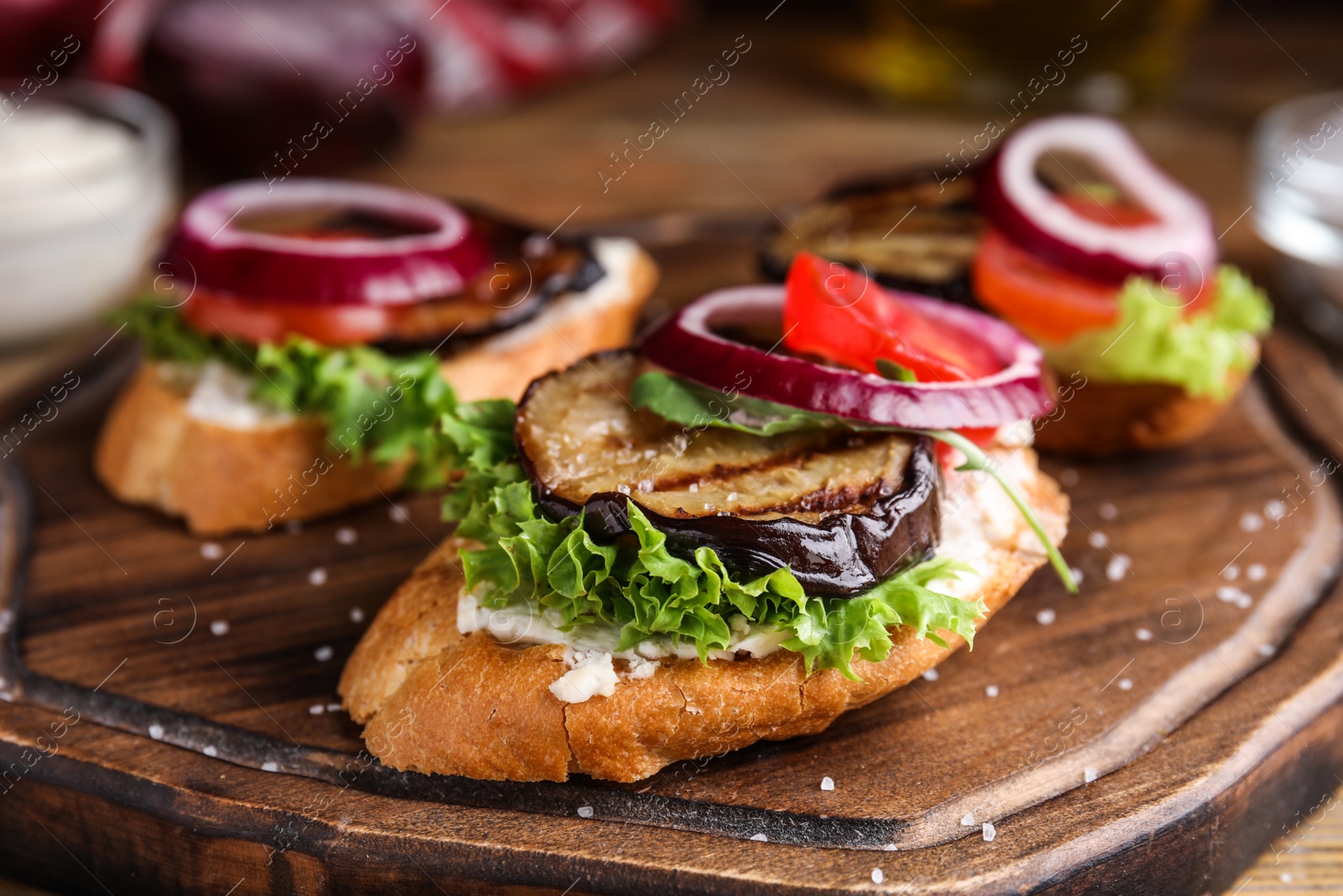 Photo of Delicious eggplant sandwiches served on wooden board, closeup