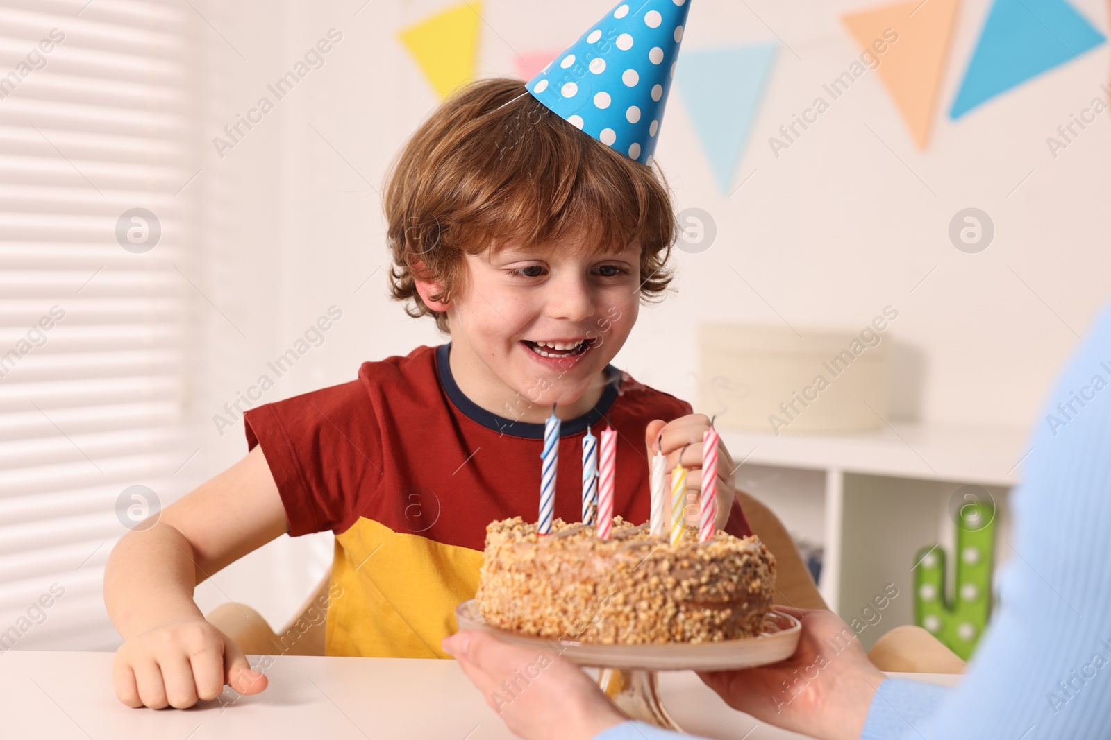 Photo of Birthday celebration. Mother holding tasty cake near her son indoors