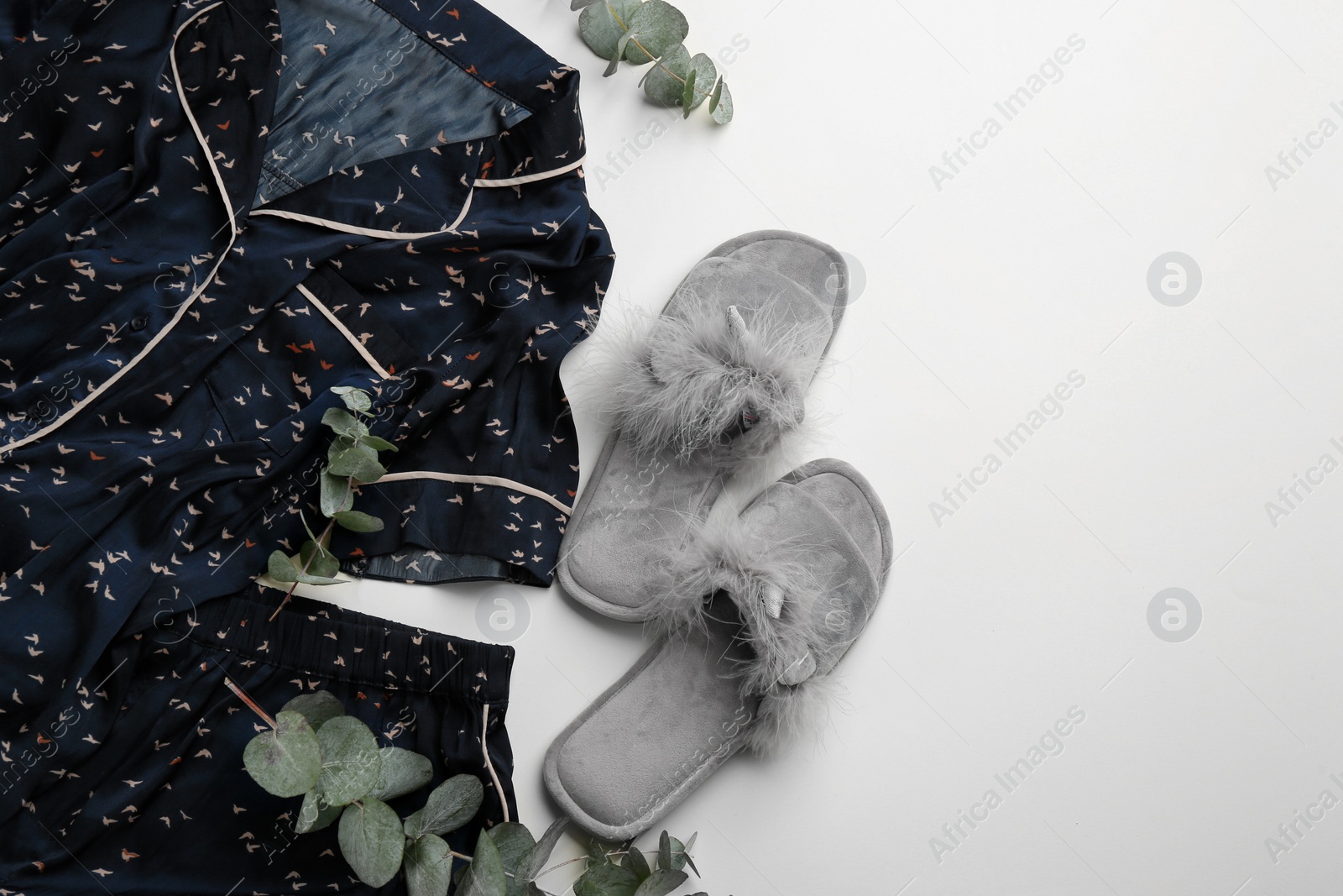 Photo of Pair of fluffy slippers, pajamas and space for text on beige background, flat lay. Comfortable home outfit