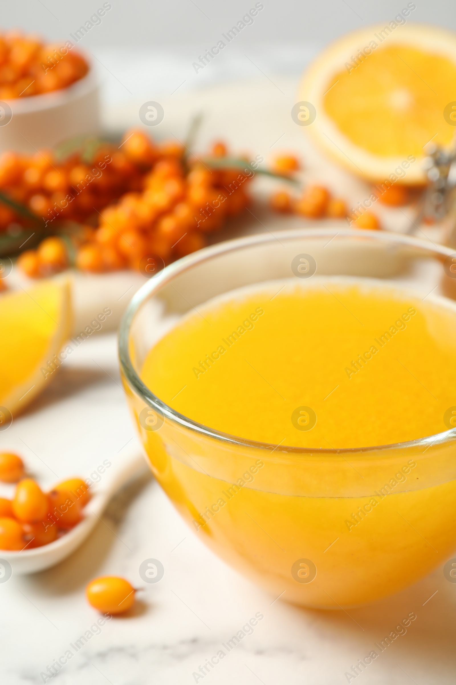 Photo of Fresh sea buckthorn tea on white marble table, closeup