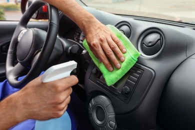 Photo of Man cleaning automobile dashboard with duster and detergent, closeup. Car wash service