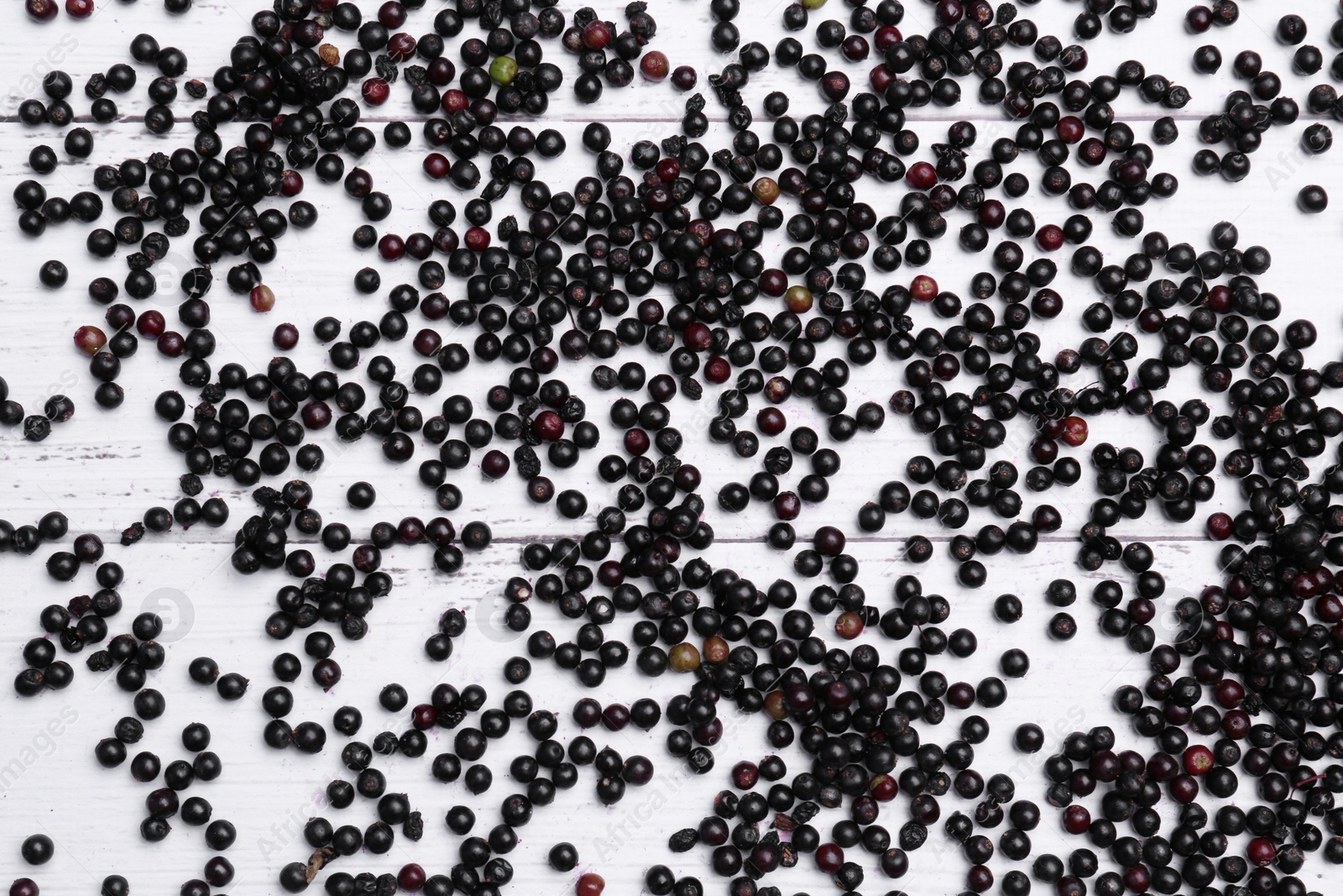 Photo of Tasty elderberries (Sambucus) on white wooden table, flat lay