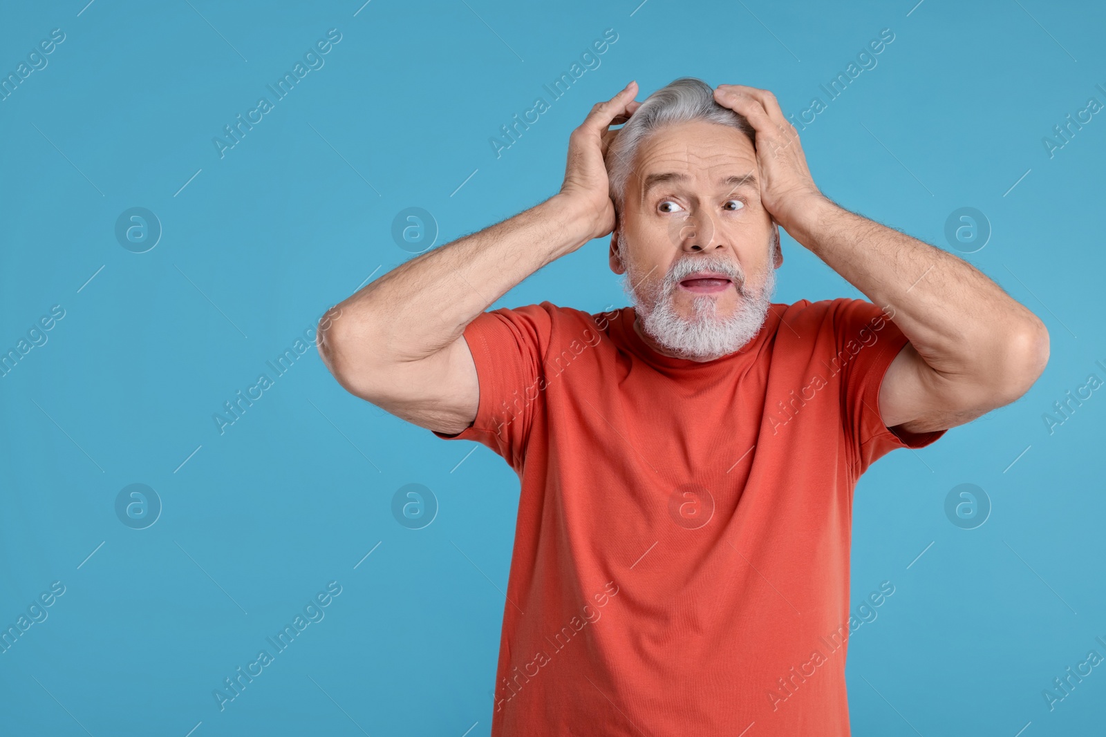 Photo of Portrait of surprised senior man on light blue background, space for text