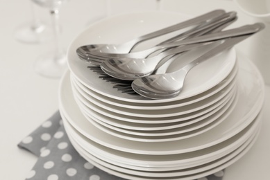 Photo of Stack of clean dishes with cutlery on table