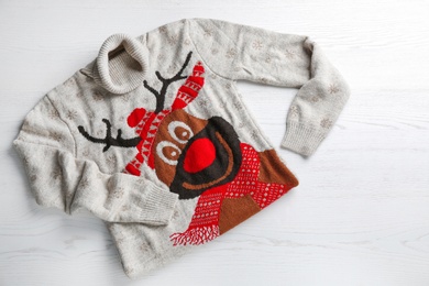 Warm Christmas sweater with deer on white table, top view