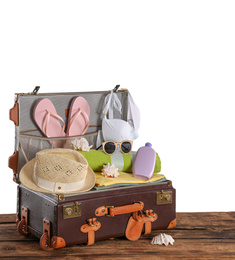 Photo of Open vintage suitcase with different beach objects packed for summer vacation on wooden table against white background