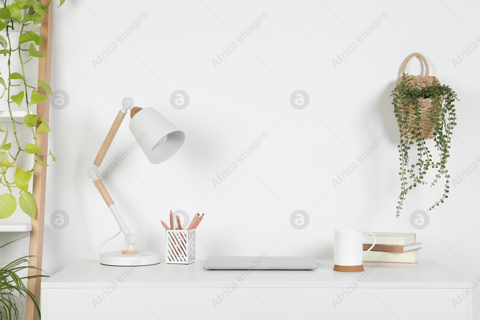 Photo of Cozy workspace with laptop, lamp and stationery on wooden desk at home