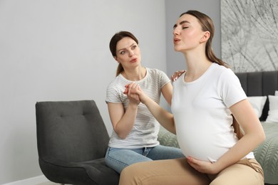 Doula taking care of pregnant woman in bedroom. Preparation for child birth