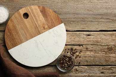 Photo of Cutting board, peppercorns and salt on old wooden table, flat lay. Space for text