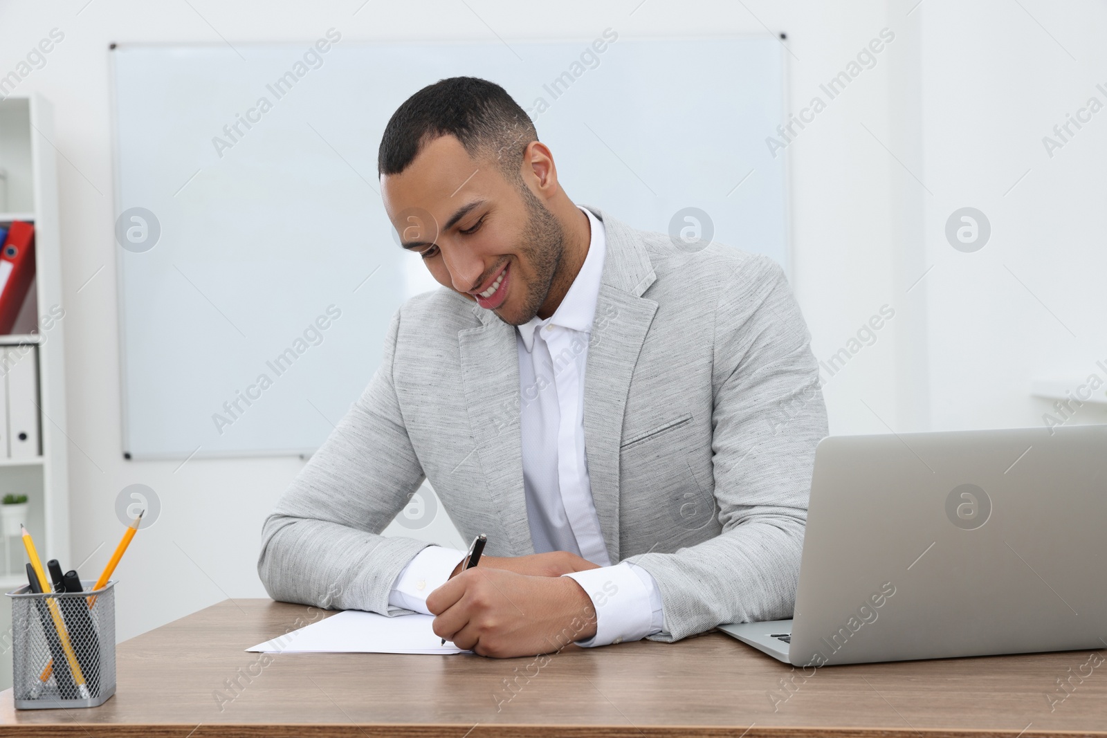 Photo of Happy young intern working at table in modern office