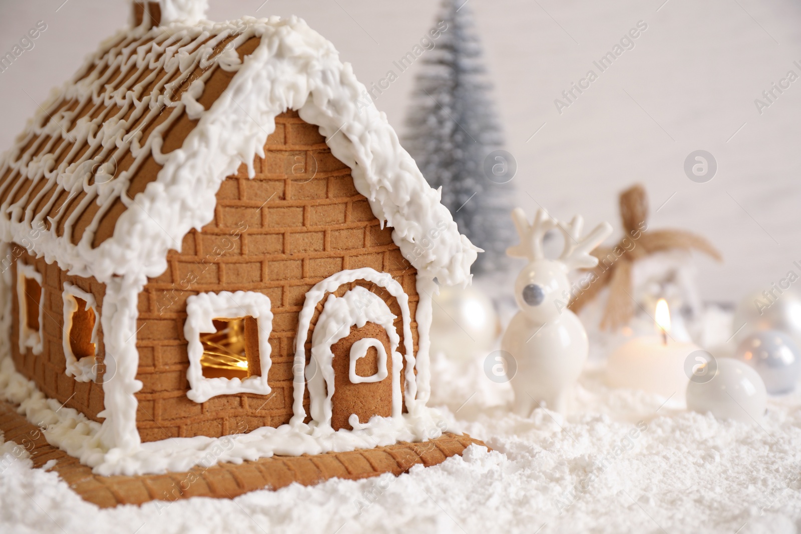 Photo of Beautiful gingerbread house decorated with icing on snow, closeup