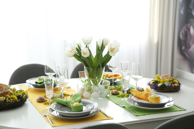 Photo of Festive Easter table setting with beautiful white tulips and eggs indoors