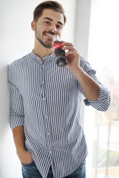 Photo of MYKOLAIV, UKRAINE - NOVEMBER 28, 2018: Young man with bottle of Coca-Cola indoors