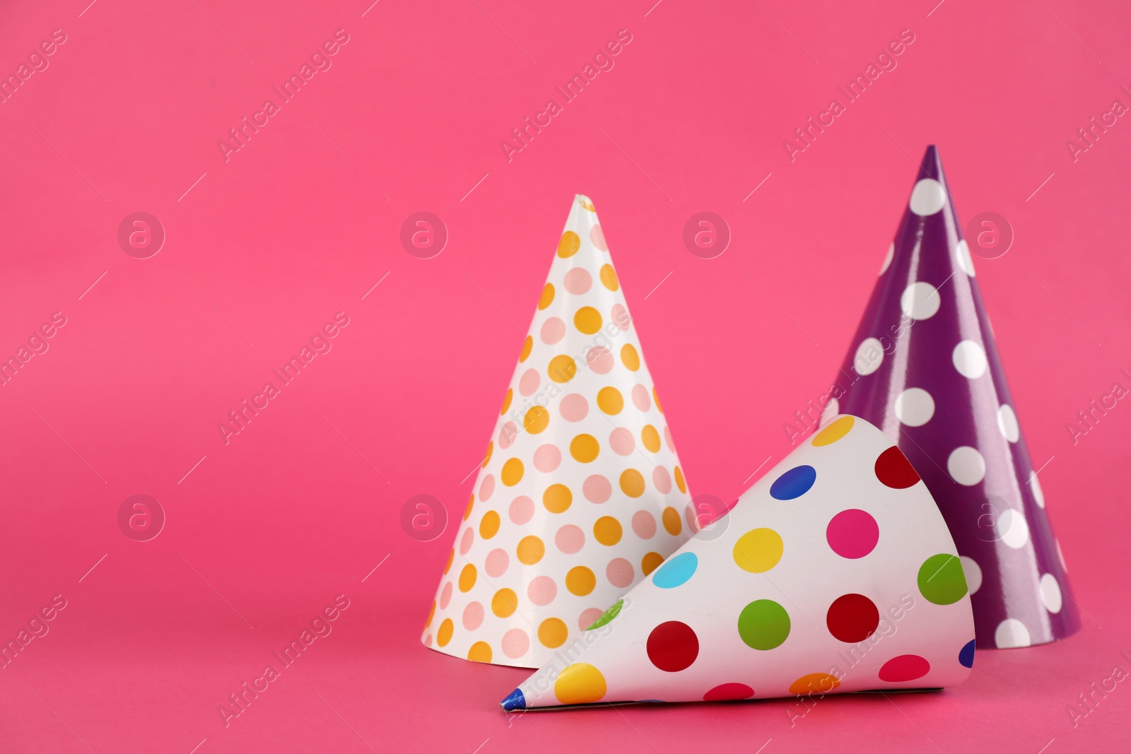 Photo of Bright party hats on pink background. Space for text