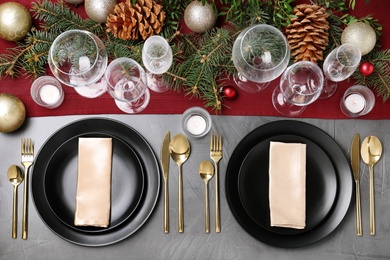 Photo of Christmas table setting with plates, cutlery, napkins and festive decor on grey background, flat lay