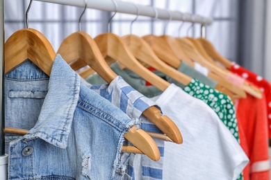 Photo of Stylish clothes hanging on wardrobe rack indoors, closeup