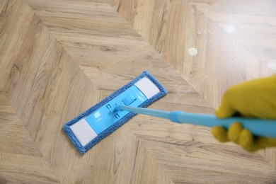 Photo of Janitor cleaning parquet floor with mop, closeup