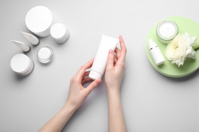 Photo of Woman holding tube of cream on light background, top view