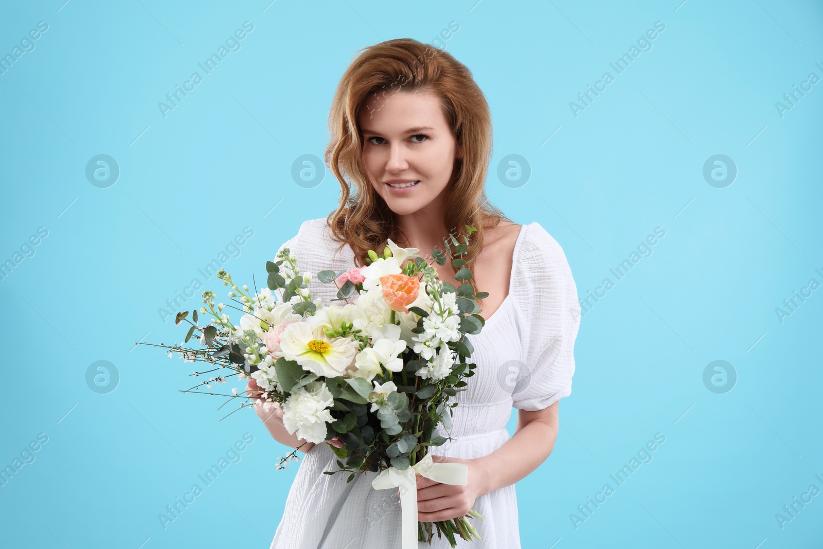 Photo of Beautiful woman with bouquet of flowers on light blue background