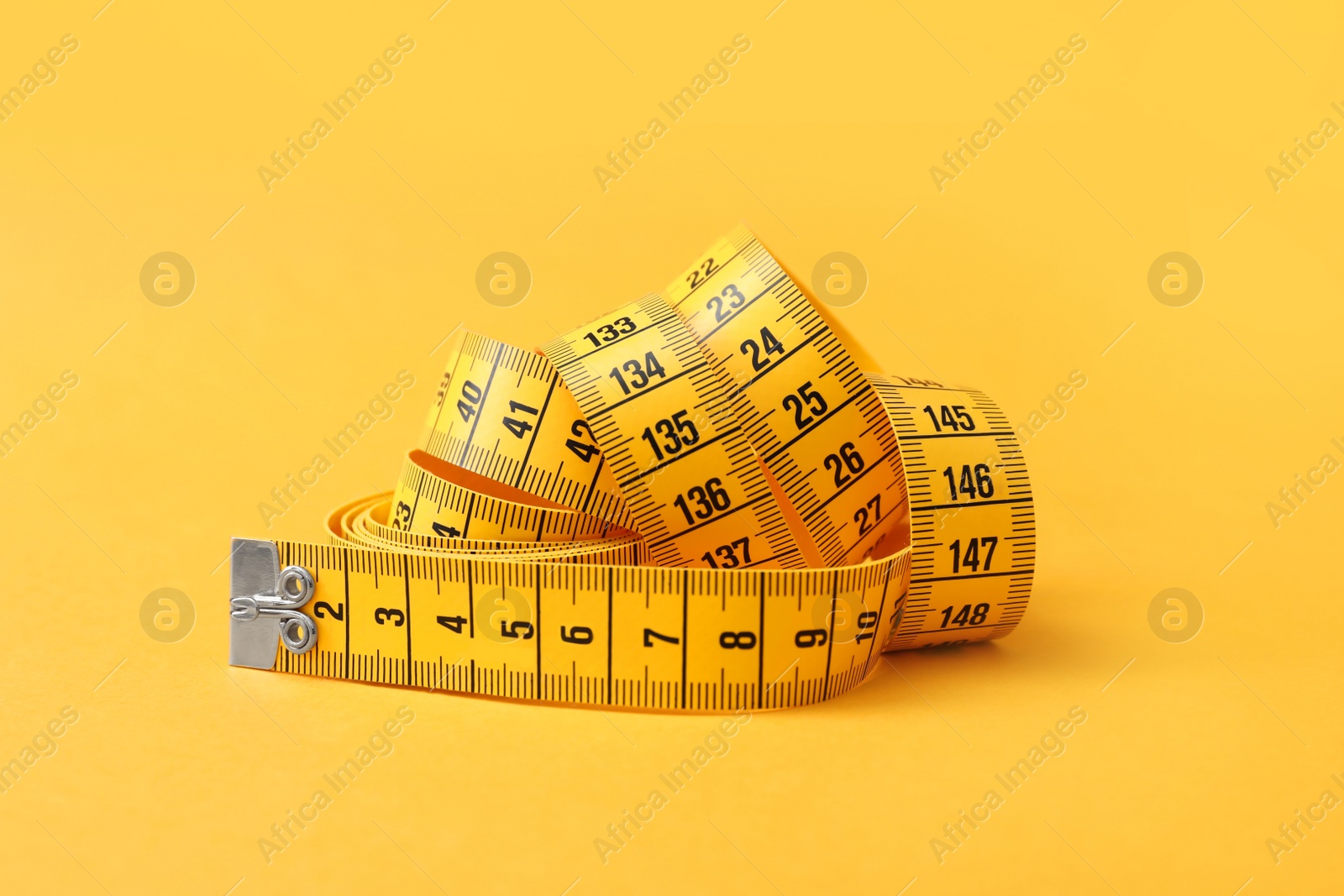 Photo of New measuring tape on orange background, closeup