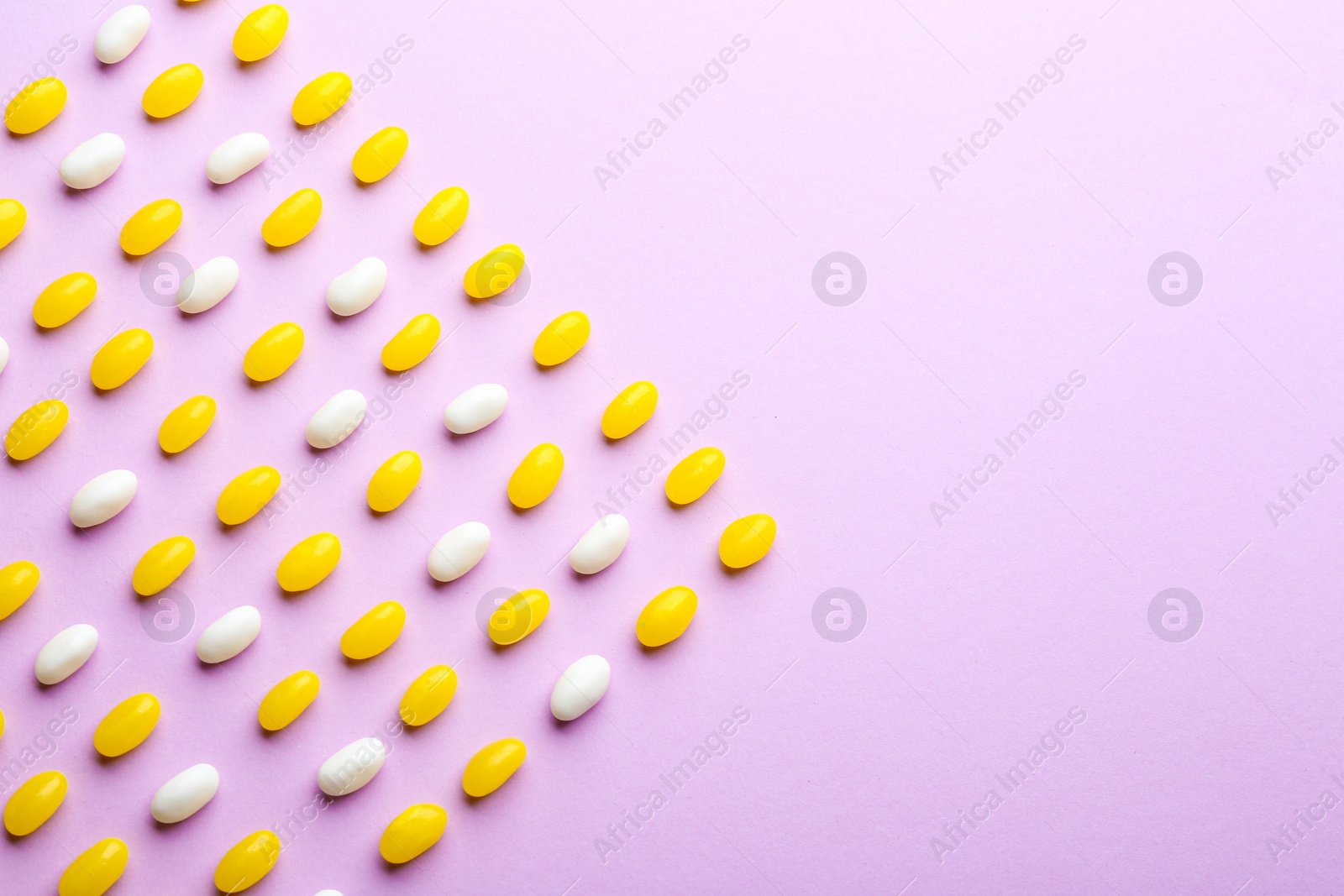 Photo of Colorful jelly beans on lilac background, flat lay. Space for text