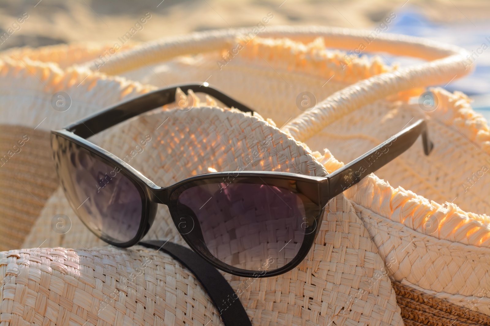 Photo of Hat and bag with beautiful sunglasses on sandy beach, closeup