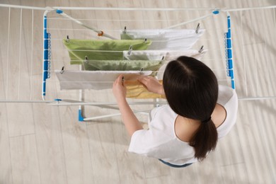 Photo of Woman hanging clean terry towels on drying rack, above view